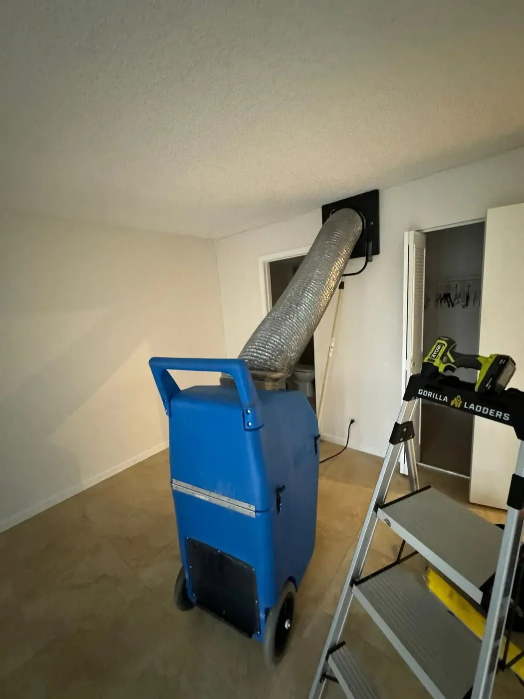 A portable air scrubber connected with flexible duct to a ceiling vent during a duct cleaning