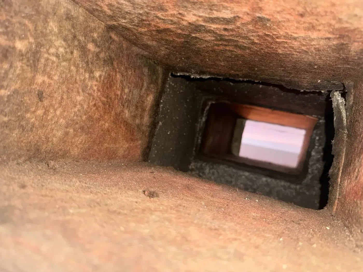 A rectangular duct interior with a heavy dust layer across every surface