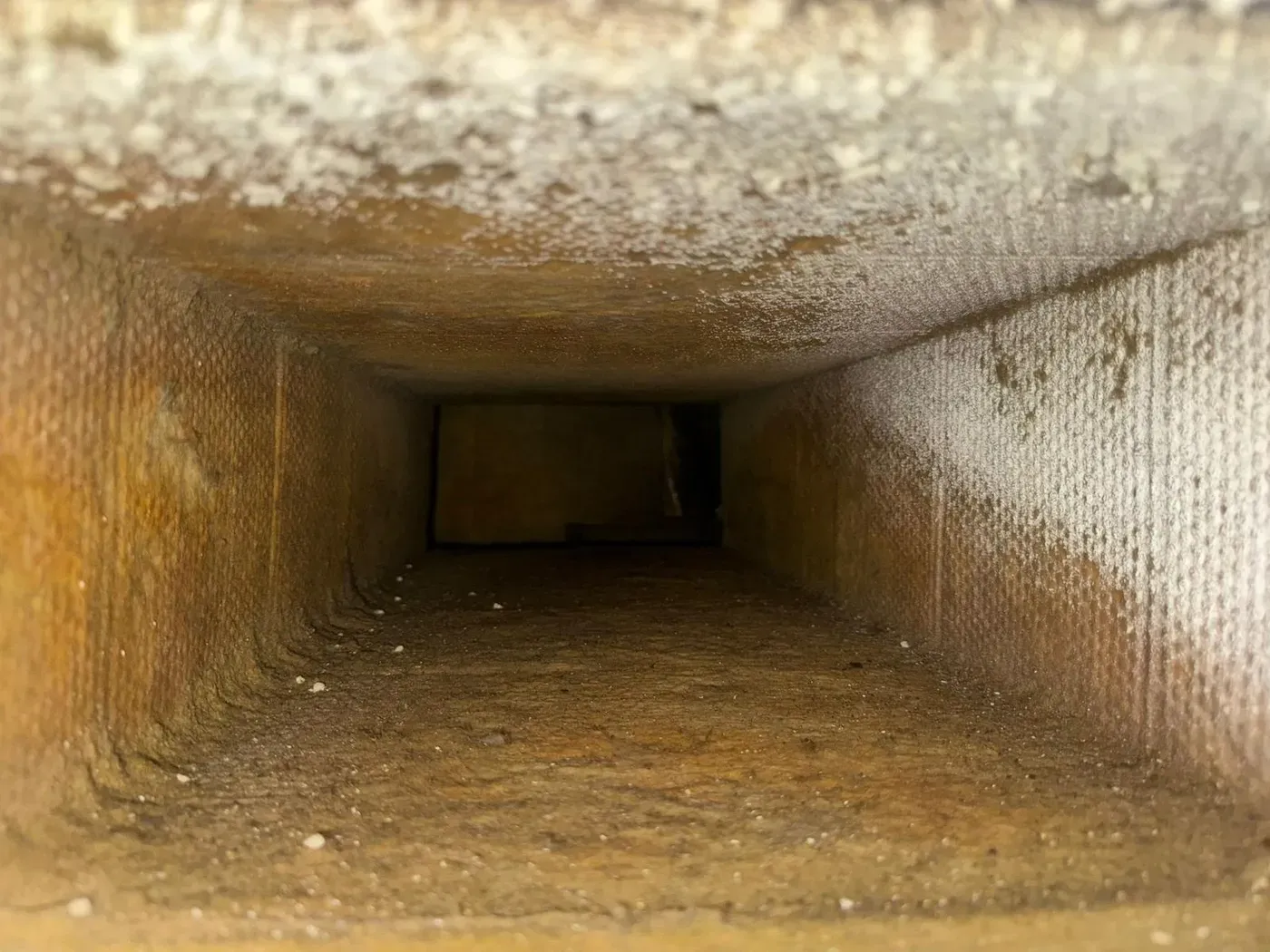 Inside a sheet-metal supply trunk coated end to end in gray dust