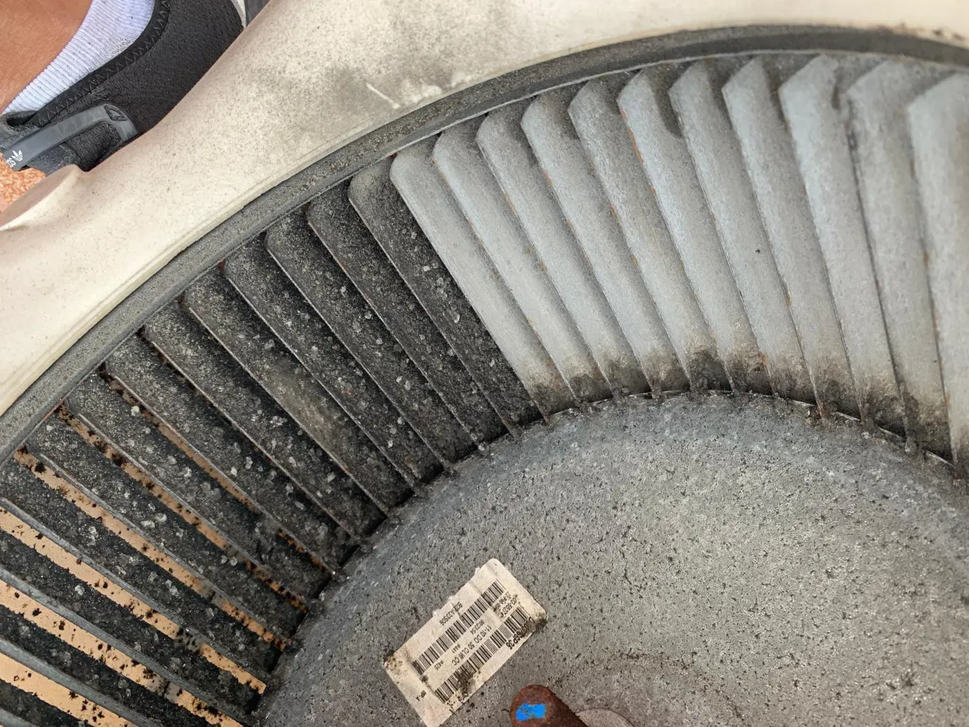A furnace blower wheel caked in dust with the blades nearly buried